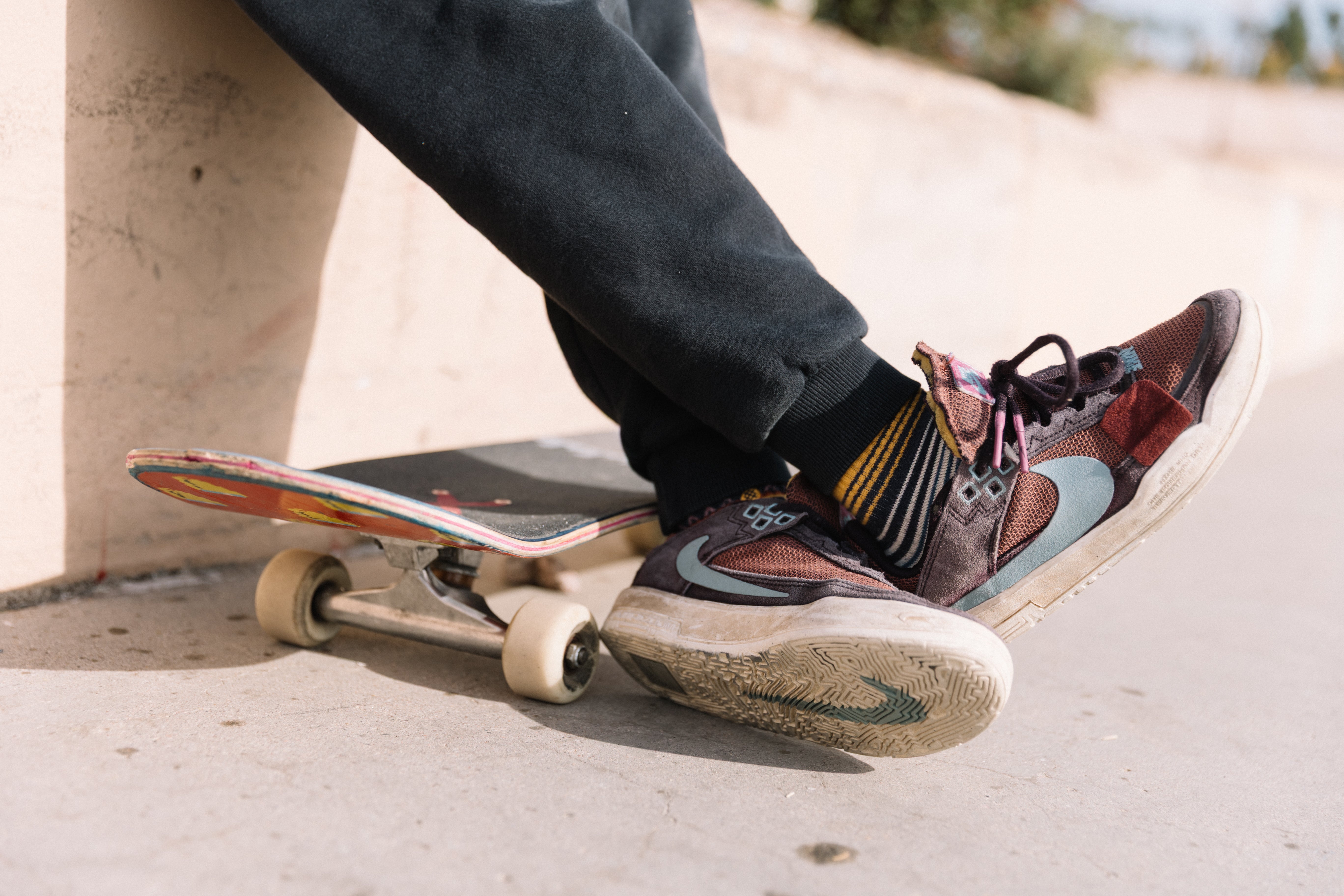 Skater wearing colorful sneakers with a maroon TrickTape patch at the local skatepark